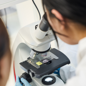 Close-up of young scientist looking through a microscope