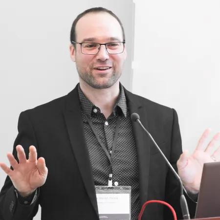 A man in a suit standing behind a lectern